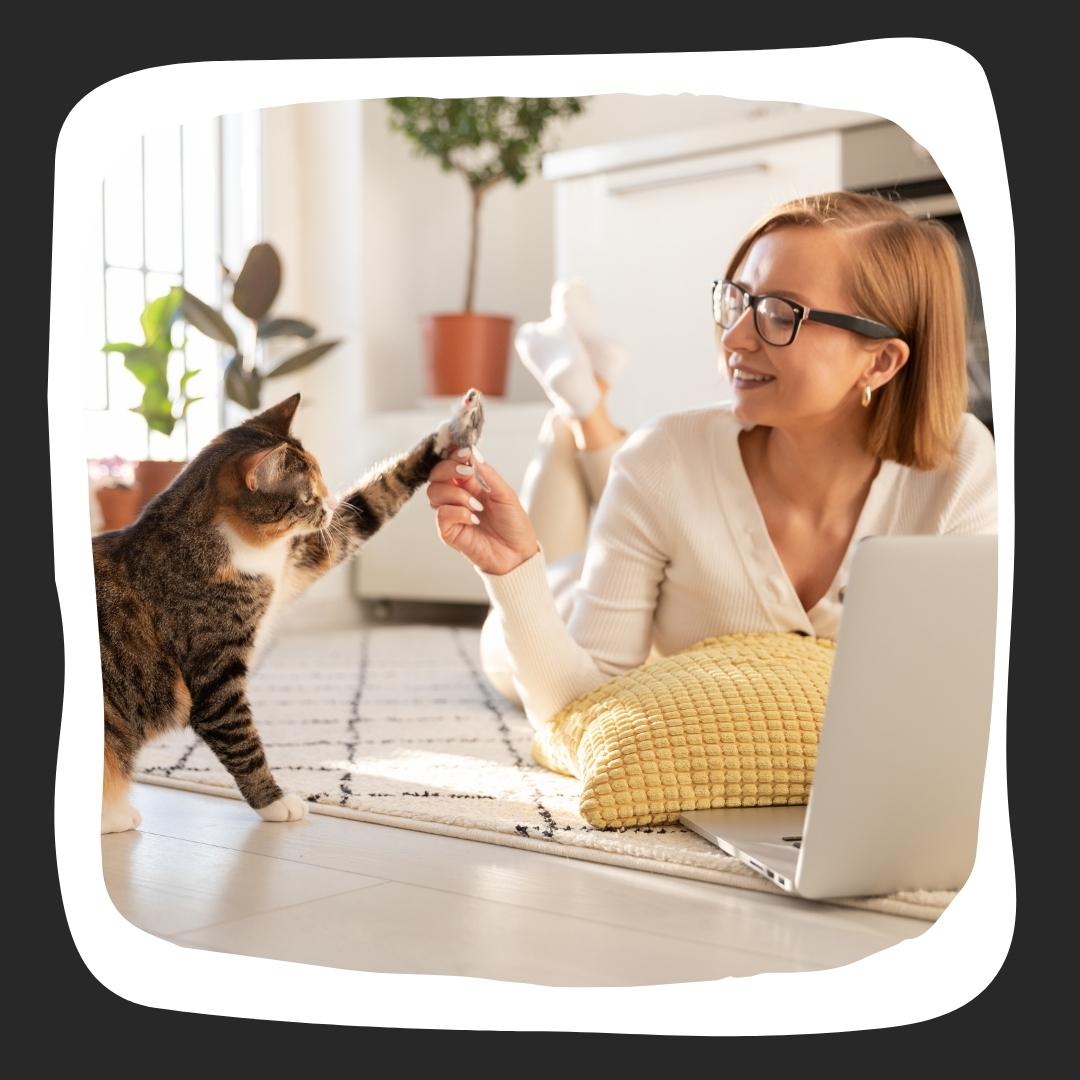 Latin woman lying on the floor giving her black and brown cat a high five